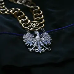 Łańcuch z godłem RP i koroną, symbol władzy, który może być dla niektórych jak zaprzeczenie mechanizm obronny, gdy rzeczywistość jest trudna.
