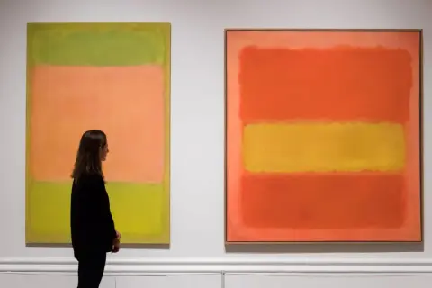 Kobieta podziwia dwa abstrakcyjne obrazy znanych malarzy. Dzieła sztuki Rothko emanują kolorem i emocjami.