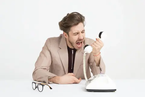 Mężczyzna krzyczy do telefonu, pokazując, co to egoizm. Obok leżą okulary.