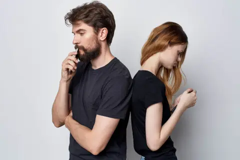 Para stoi plecami do siebie, oboje patrzą w telefony. Cisza i brak odpowiedzi na "kocham cię".